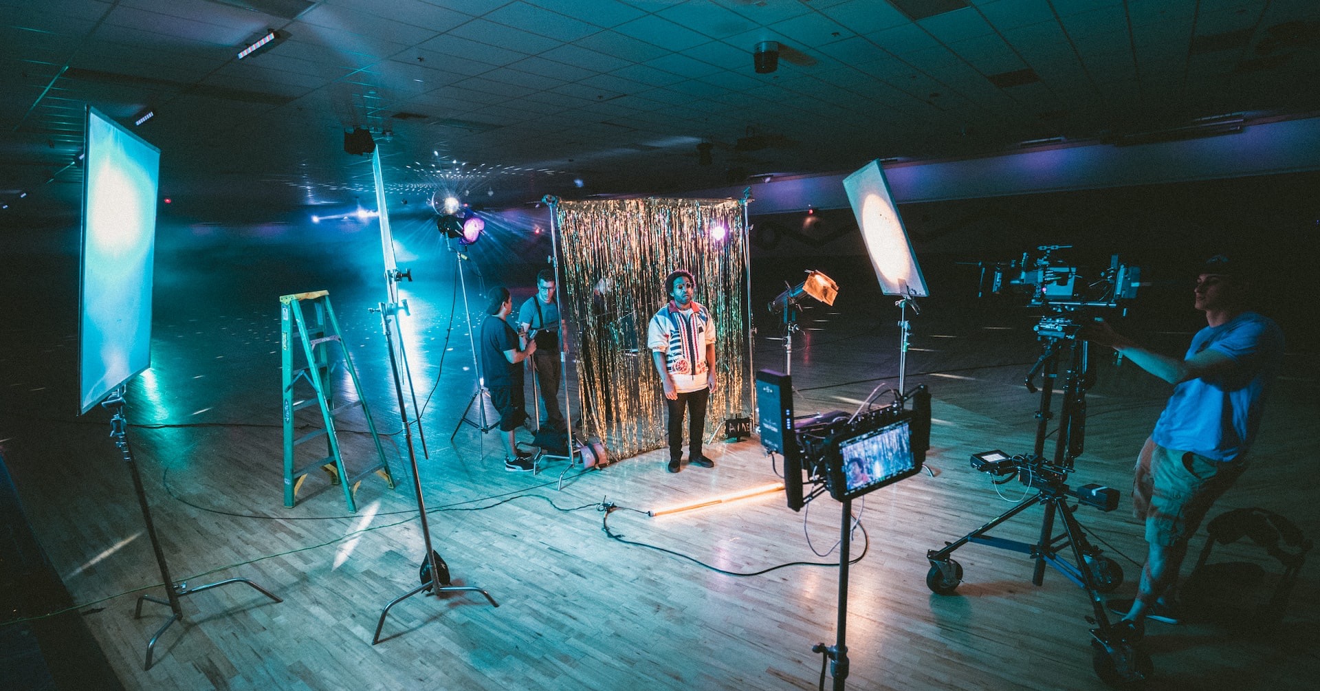 man standing in front of cameras with string lights background