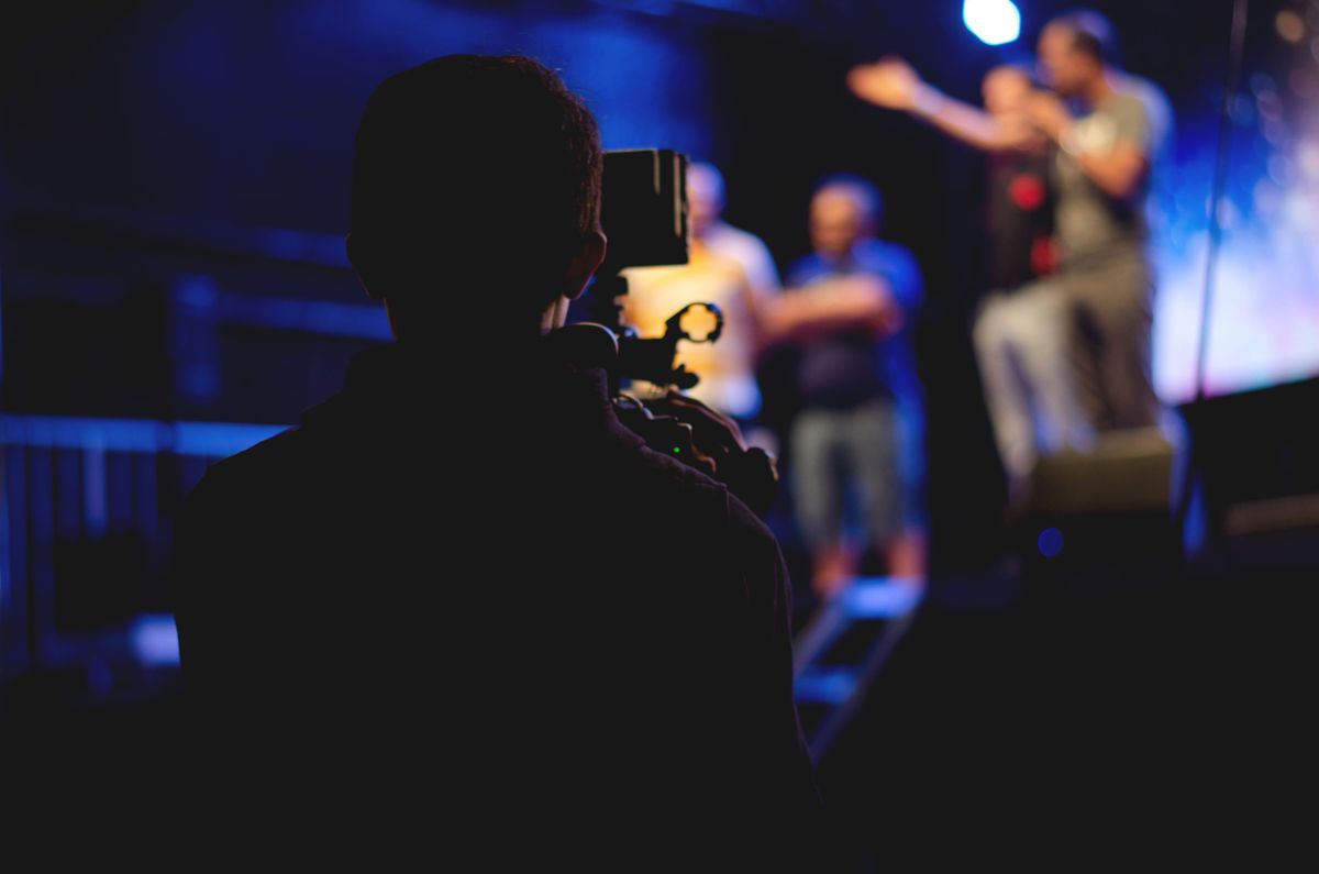 Un caméraman filme une performance de concert en direct, capturant l'action dynamique sur scène.