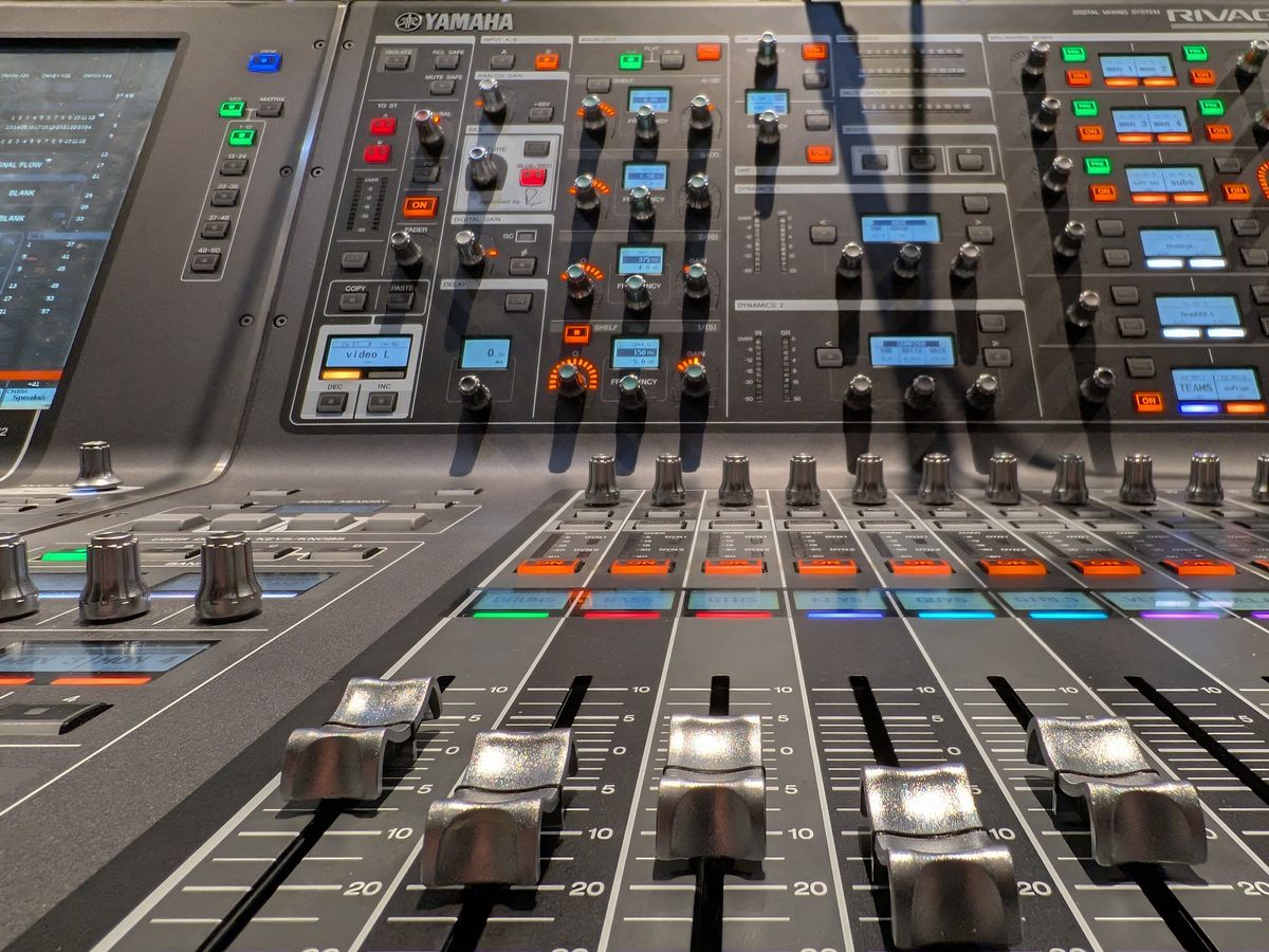 Gros plan d'une console de mixage audio numérique moderne avec faders et commandes.