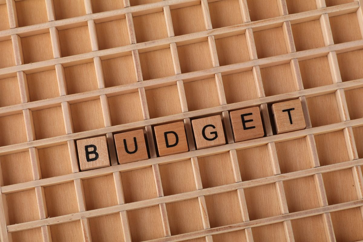 Des lettres en bois formant le mot « budget » sur un fond de grille en bois, symbolisant les finances et la planification.