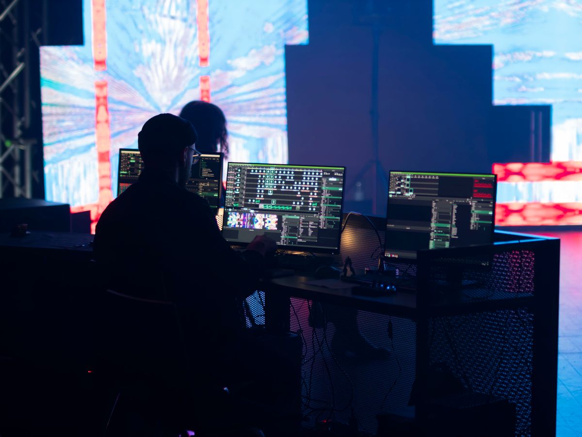 A stage technician monitors multimedia displays during a live event setup.