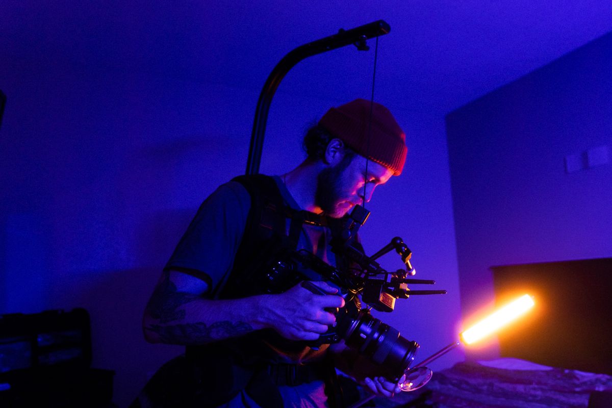 A cinematographer setting up camera equipment with unique lighting in an indoor studio.