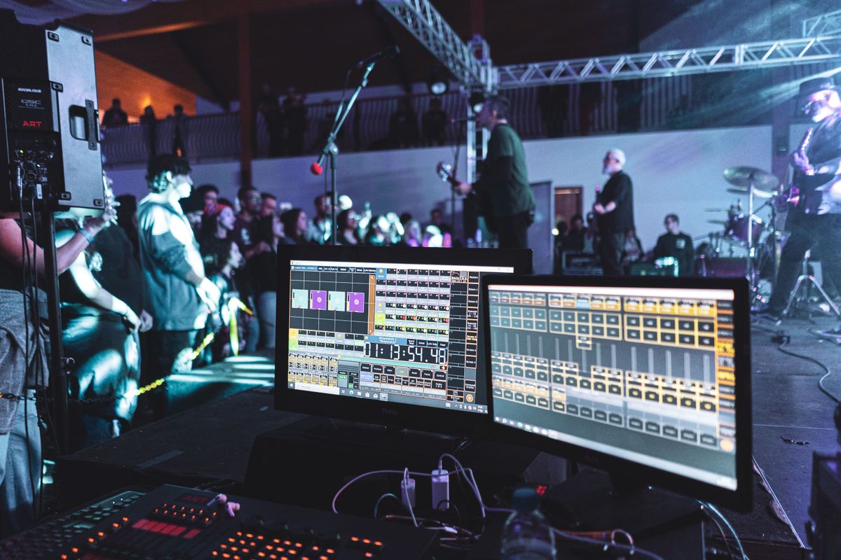 Scène de concert en direct avec installation d'ingénierie du son et groupe sur scène.